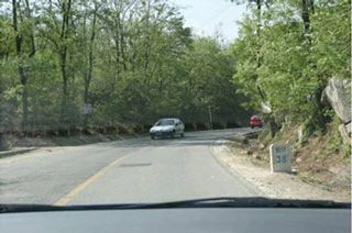 如图所示，通过前方视线受阻的弯道时，教练员应提示学员（ ）。